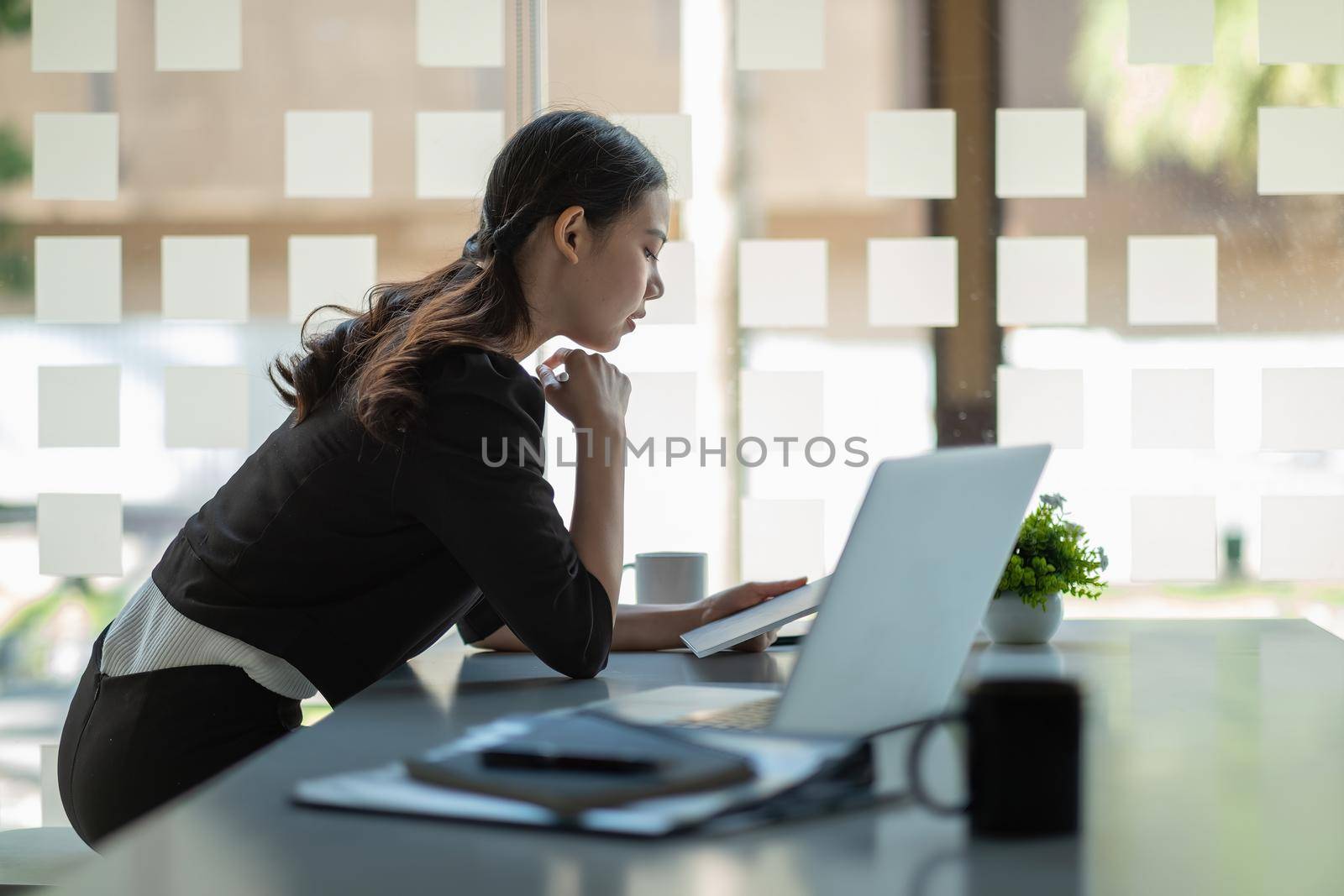 Happy Asian businesswoman using digital tablet at modern office. Concept of young people working mobile devices for marketing plan