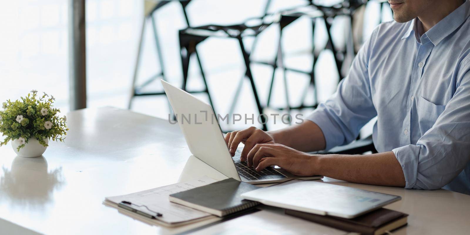 Smiling business man using laptop at office. Male hands typing on the notebook keyboard.Concept of young people work mobile devices.