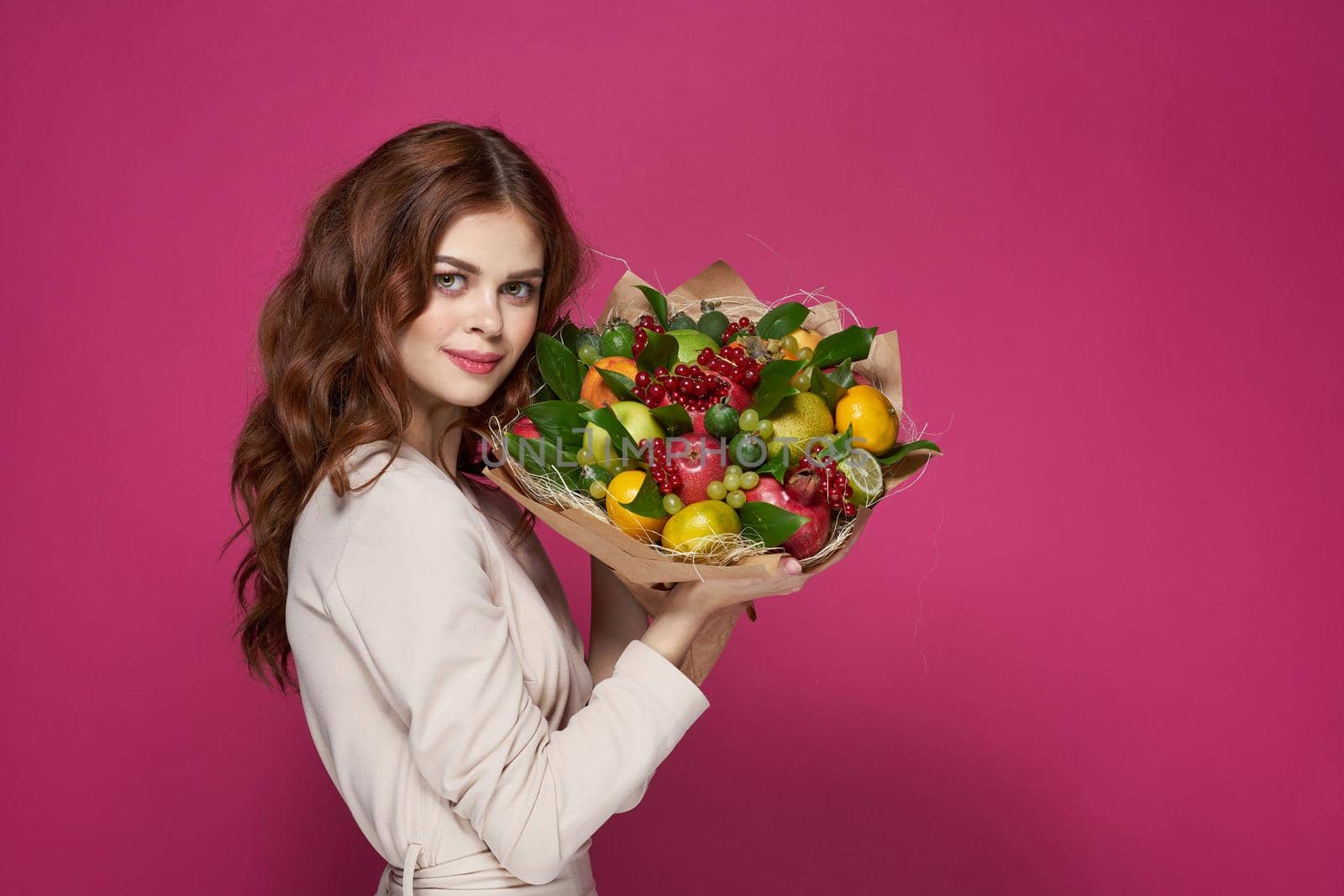 pretty woman bright makeup attractive look a bouquet of fruits pink background. High quality photo