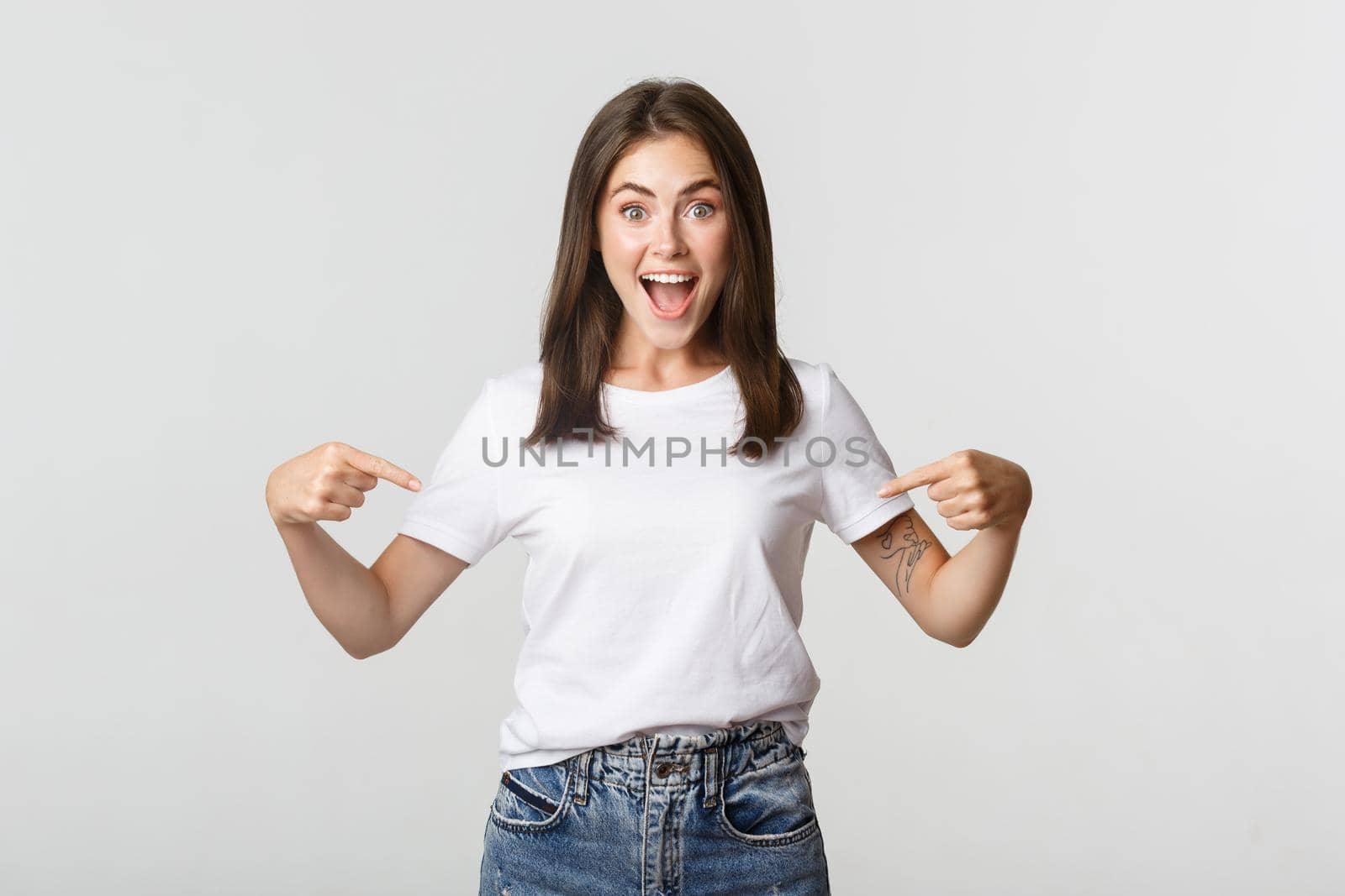 Excited happy brunette girl smiling, pointing fingers at logo, showing banner.