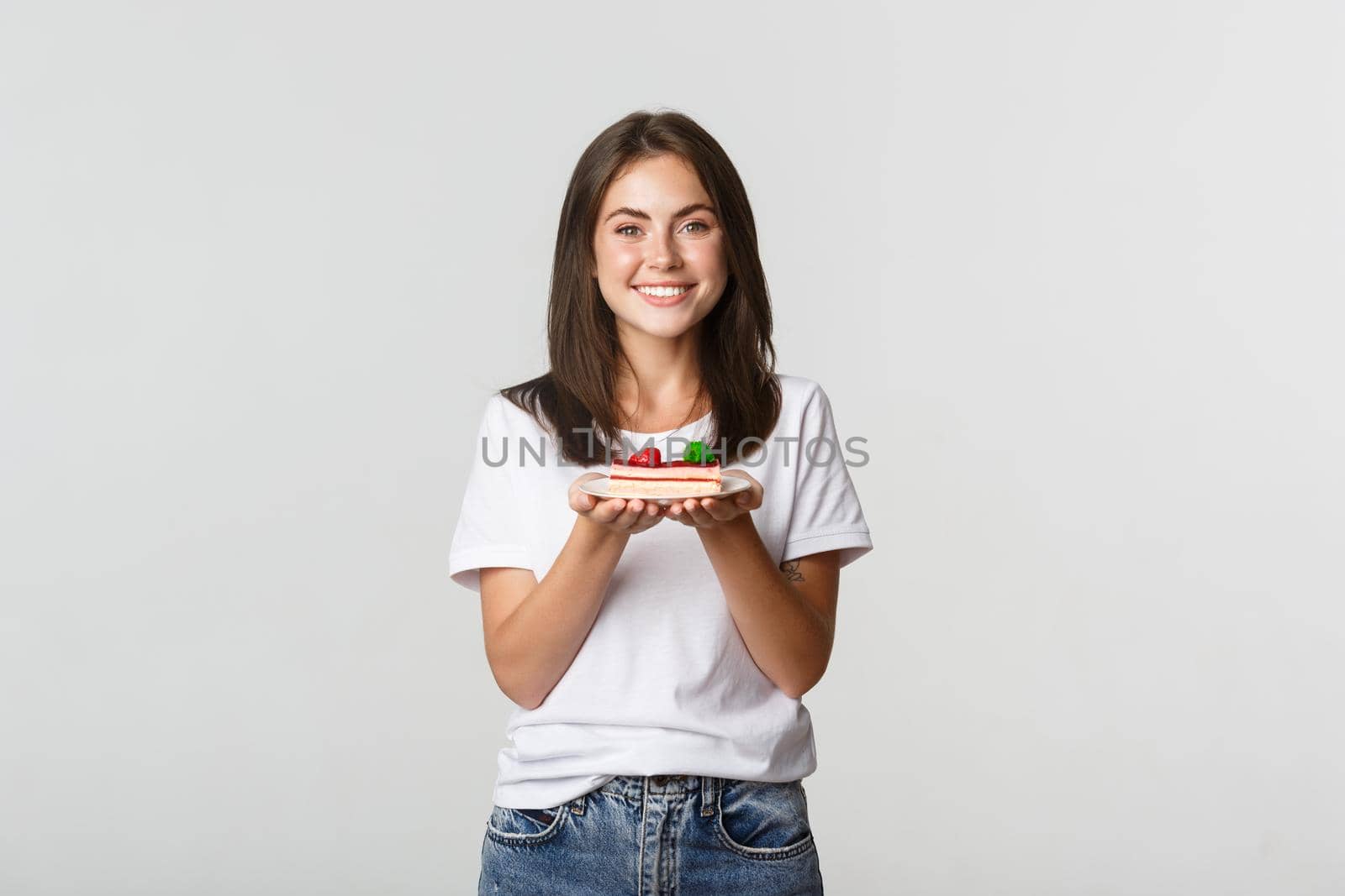Attractive brunette girl smiling happy and holding cake on plate.