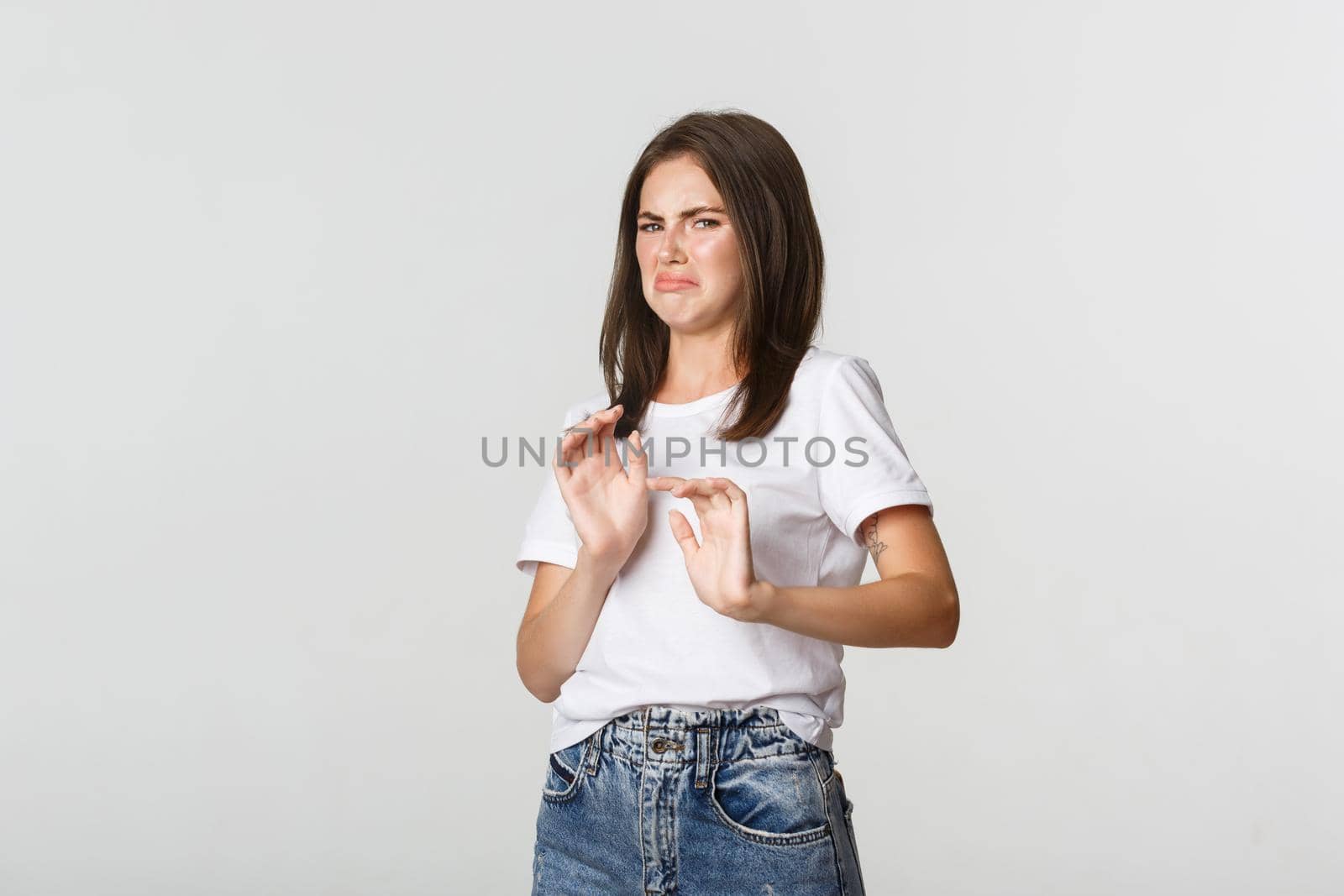 Disgusted young brunette girl grimacing and showing stop gesture, refuse awful disgusting thing by Benzoix