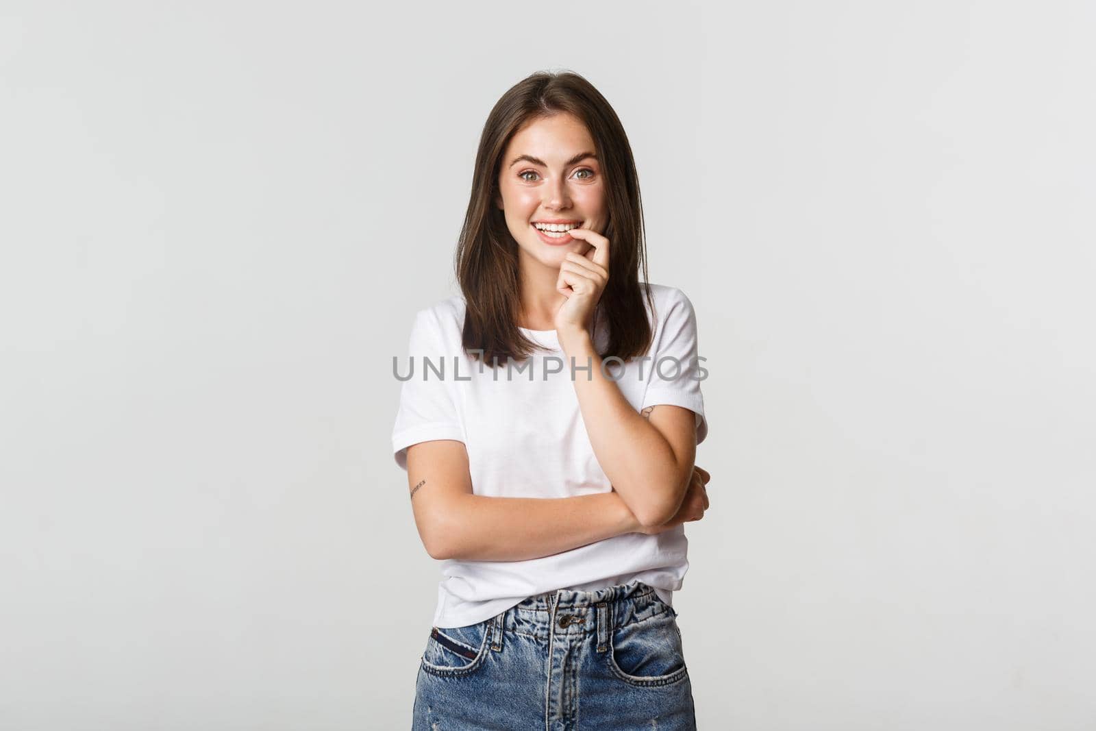 Smiling attractive girl biting finger and looking with temptation, white background by Benzoix