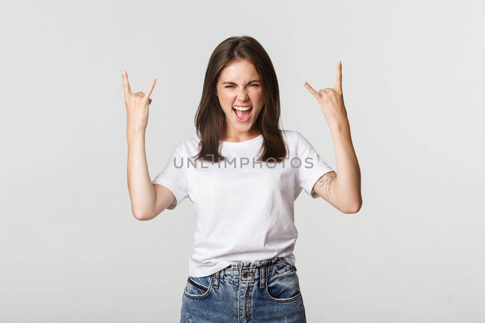 Joyful good-looking girl showing rock-on gesture and enjoying concert by Benzoix