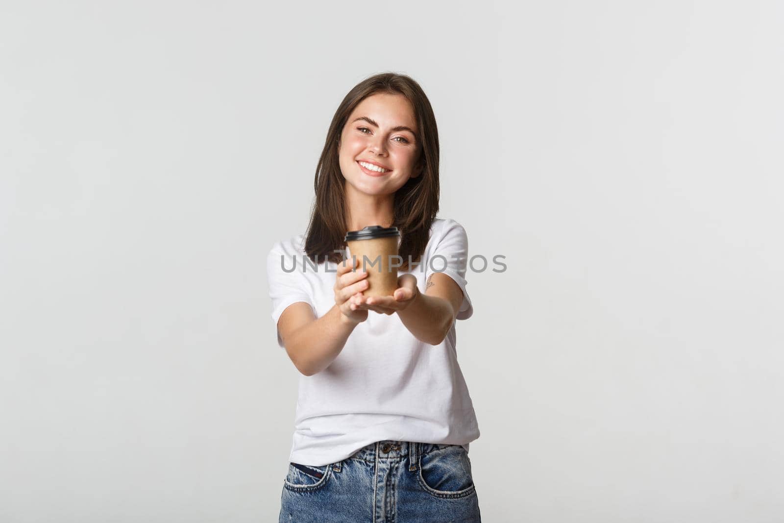 Smiling beautiful brunette woman giving you cup of coffee by Benzoix