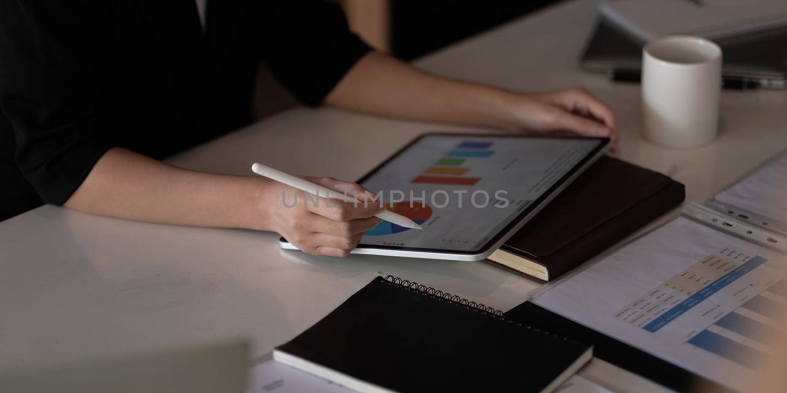 Close up hand of woman with stylus pen writing on digital tablet, touching on digital tablet screen working on laptop computer in office.
