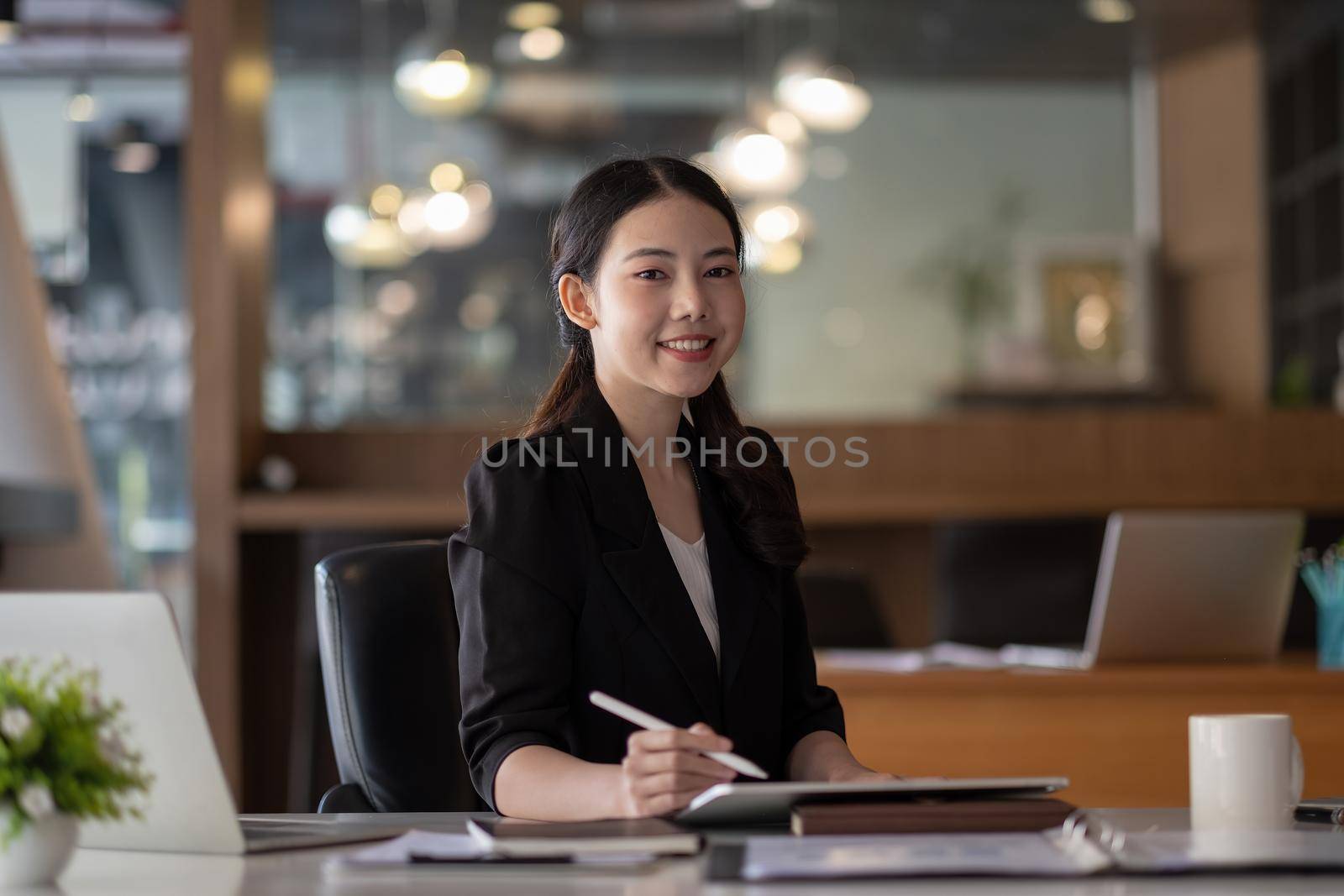 Portrait of young smiling cheerful entrepreneur in modern office working with digital tablet for financial analysis by nateemee