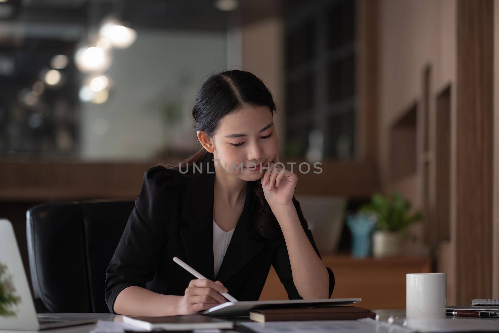 Portrait of young smiling cheerful entrepreneur in modern office working with digital tablet for financial analysis.