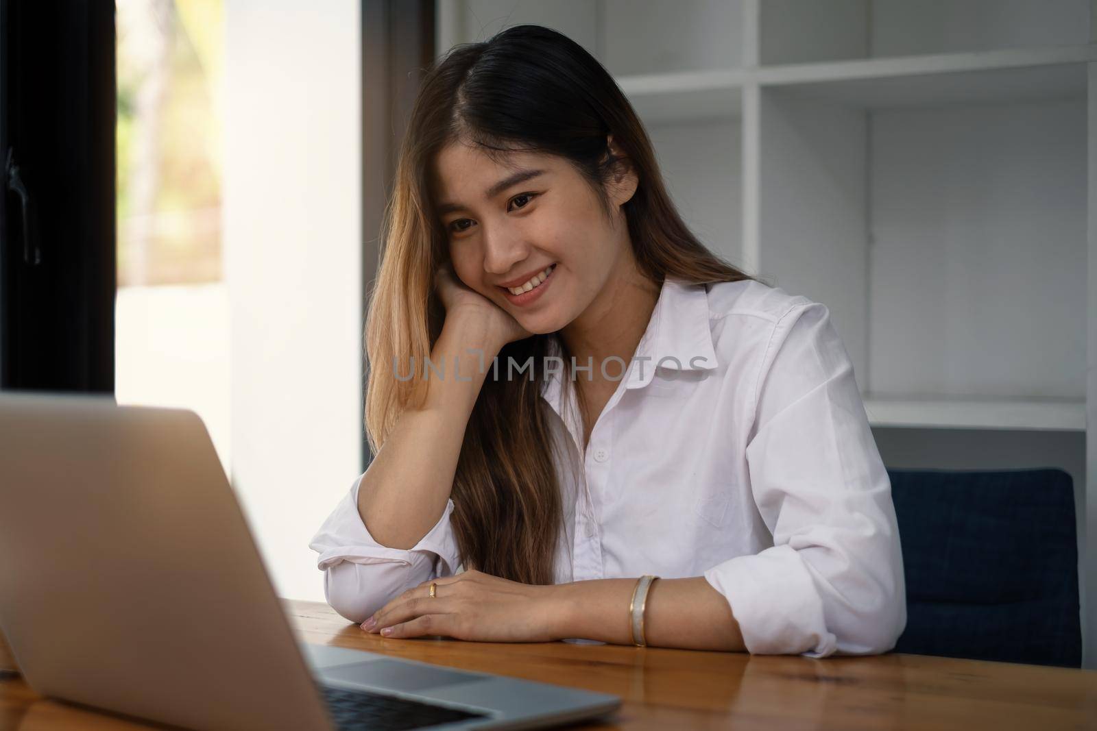 Cheerful young asian woman using laptop computer at home. Student female in living room. online learning, studying , online shopping, freelance, asean concept. by itchaznong