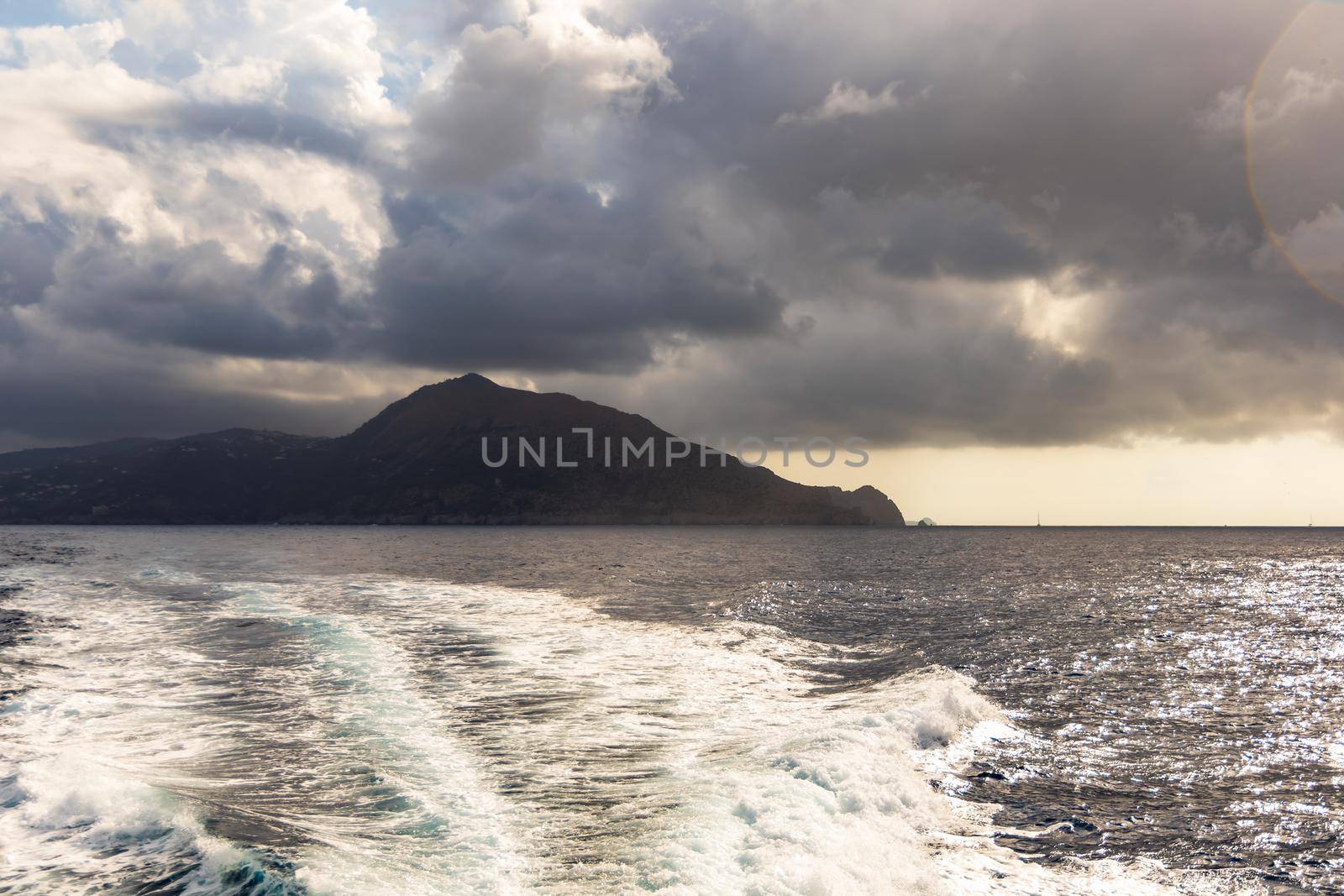 Silhouette of Capri island on Tyrrhenian Sea in Italy seen from boat with waves behind by Wierzchu