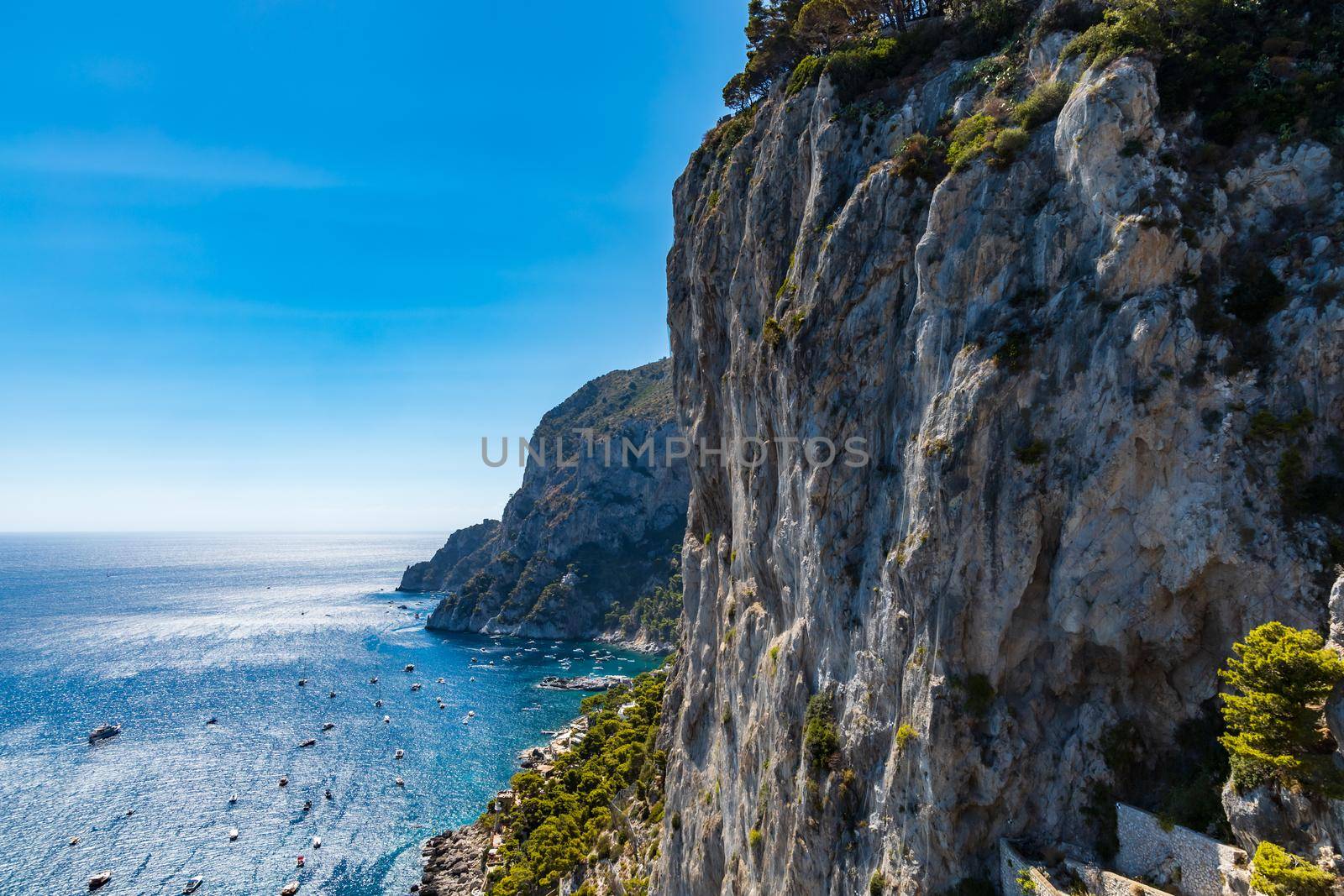 Edge of high cliff full of high green trees at sunny day on Capri island by Wierzchu