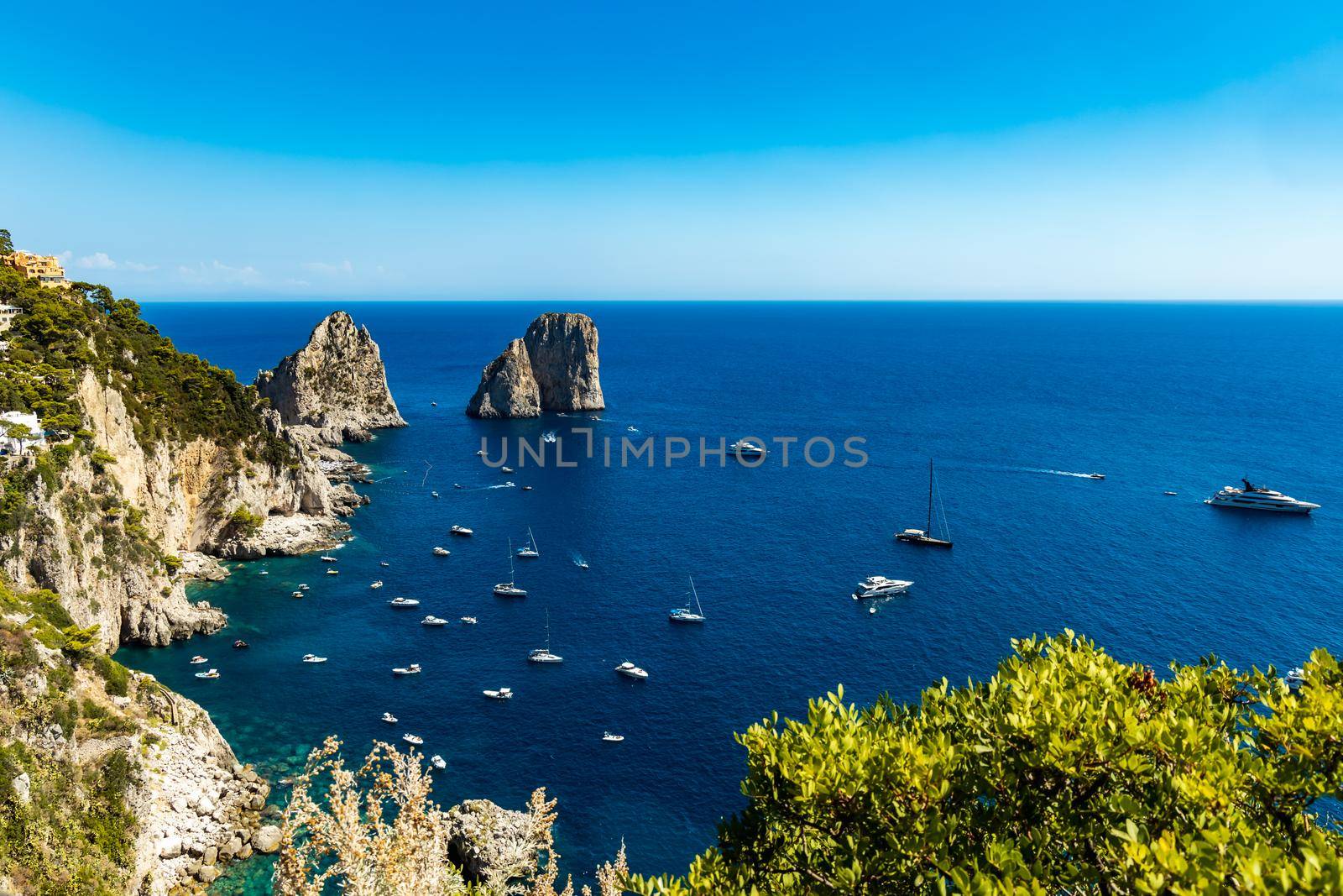 Beautiful panorama of small bay full of small ships and boats next to 
Faraglioni di Mezzo
 and Capri island 