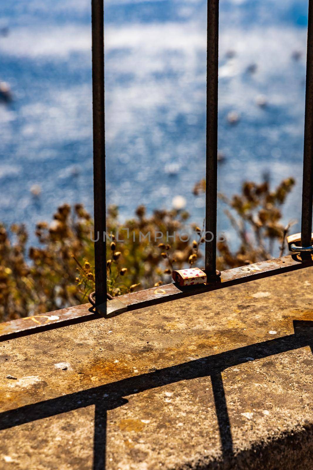 Small padlock with red hears pattern on metal fence by Wierzchu