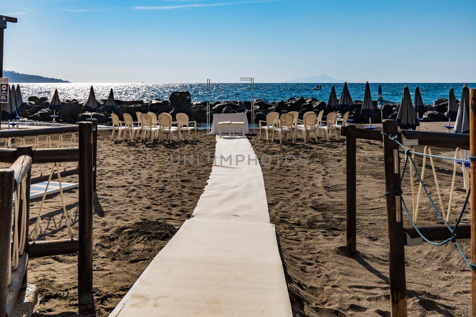 Preparations of wedding party on small beach next to sea and big rocks