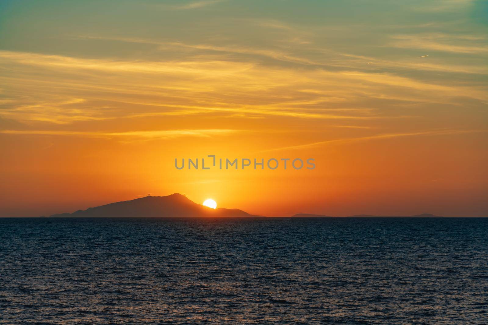 Beautiful sunset with sun hiding behind Ischia island over Tyrrhenian Sea