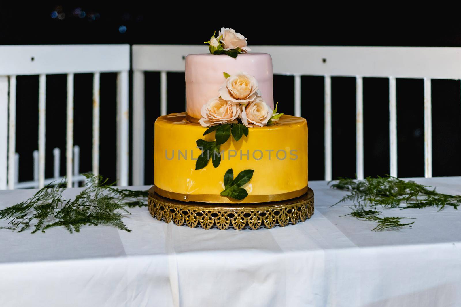 Pink and yellow wedding cake standing on table with colorful and beauty decorations around by Wierzchu