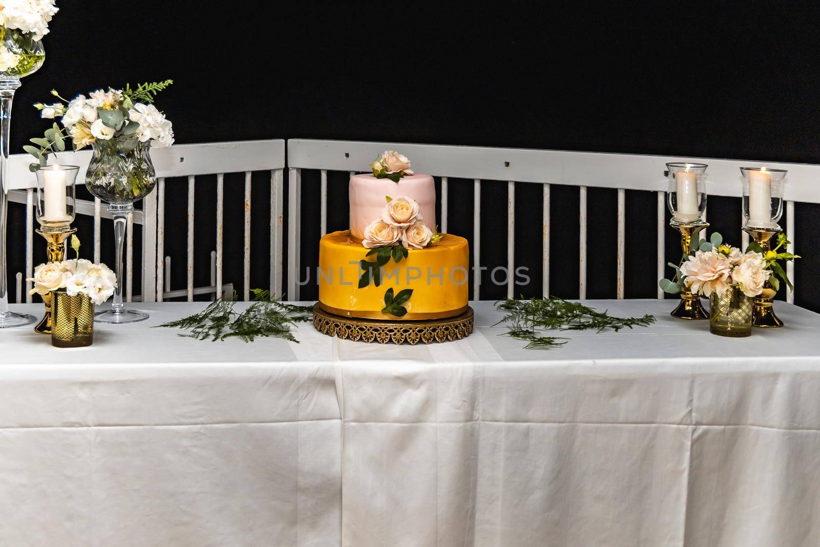 Pink and yellow wedding cake standing on table with colorful and beauty decorations around by Wierzchu