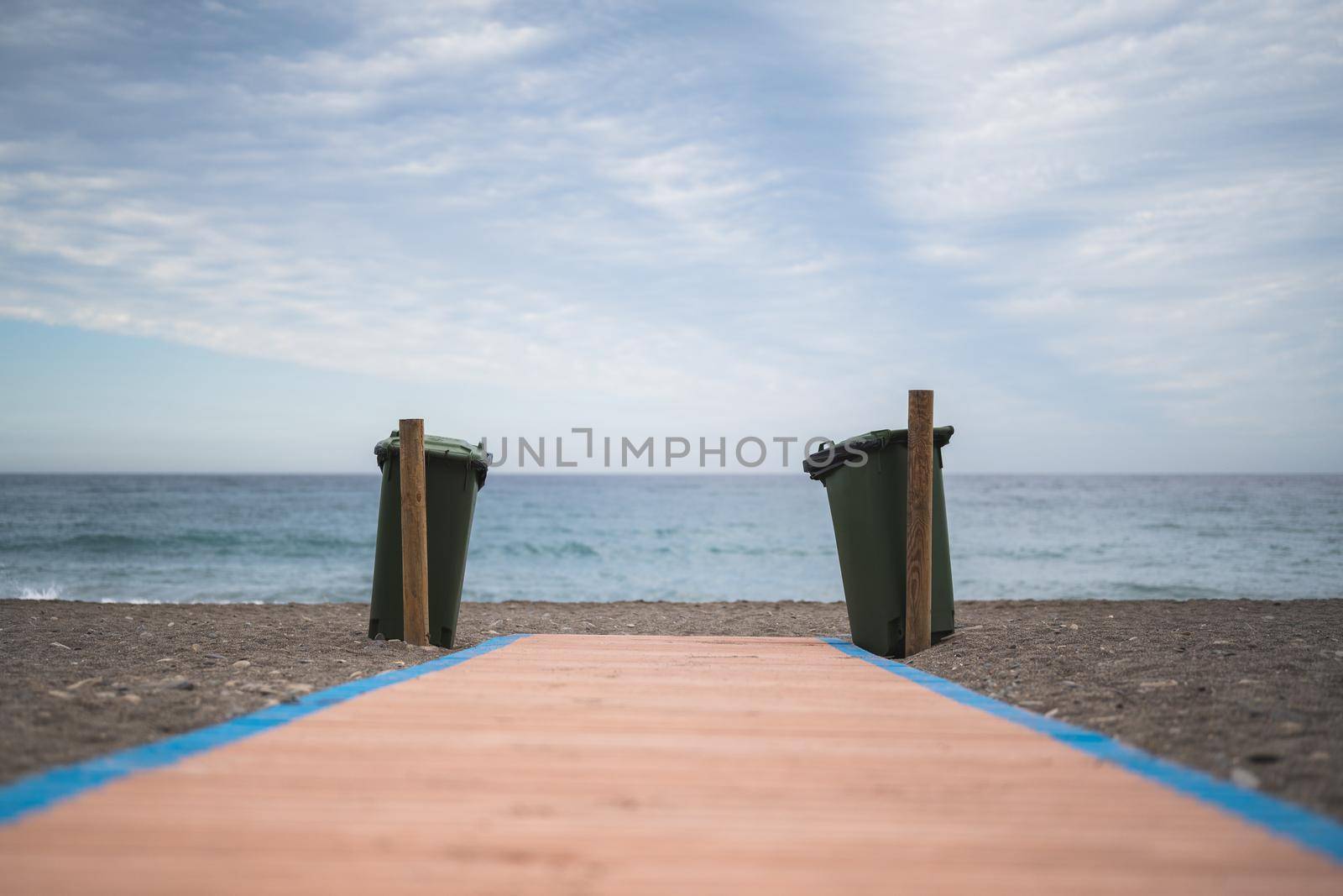 garbage bins at the end of a wooden path in front of the sea. concept of conservation of the environment.