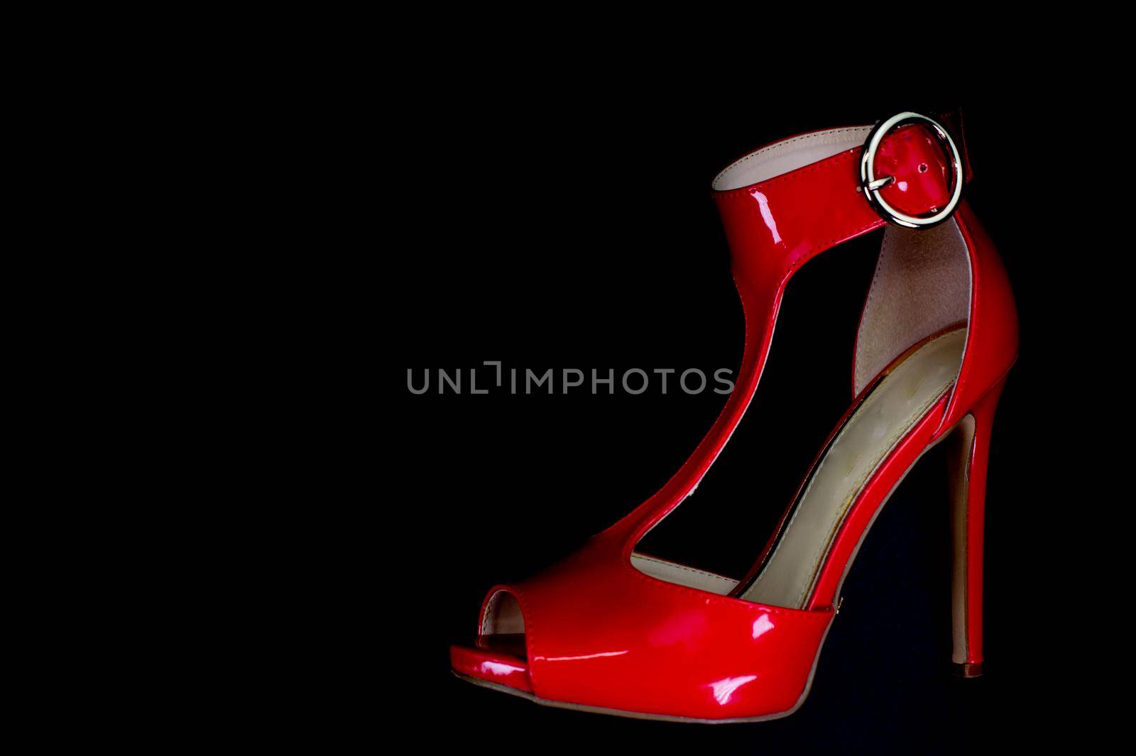 red patent leather sandal for the summer season on a black background