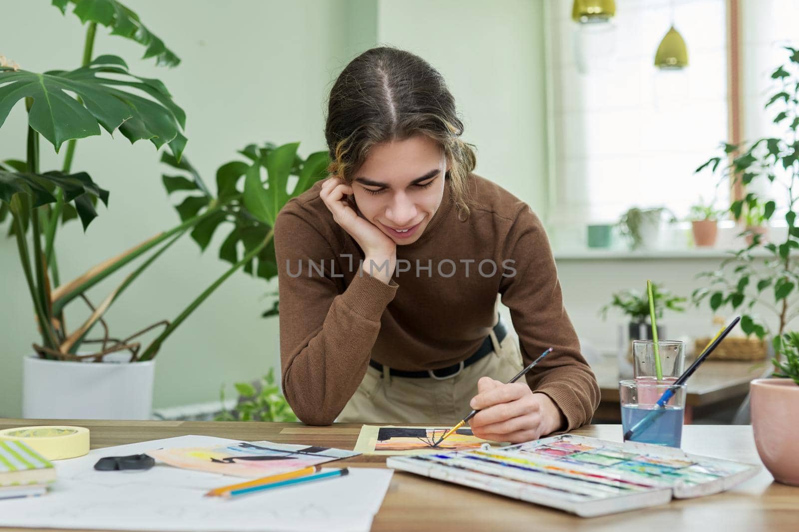 Teenager guy artist painting with watercolors at home by VH-studio