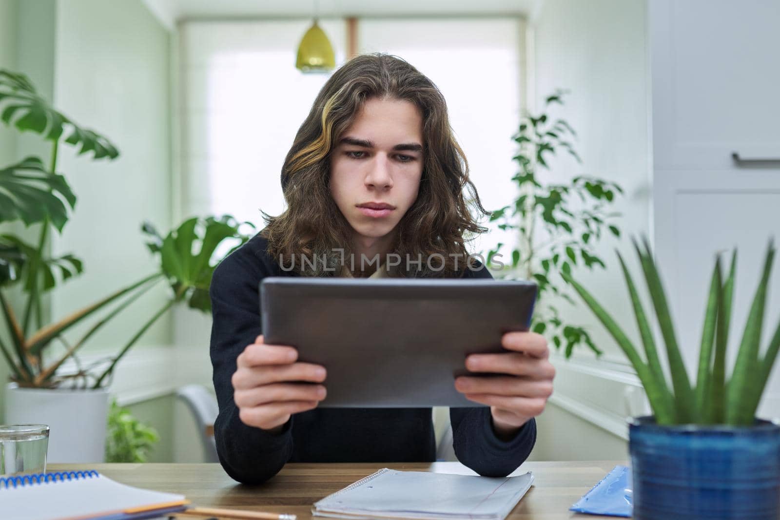 Virtual online lesson, serious teenager guy learns remotely using digital tablet. Video test, meeting, e-education, technologies in teaching, adolescence, distance learning, modern college school