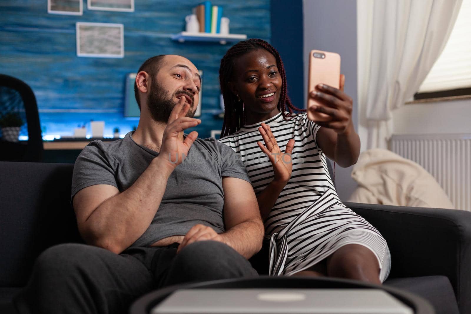 Interracial couple waving at camera talking on video call by DCStudio
