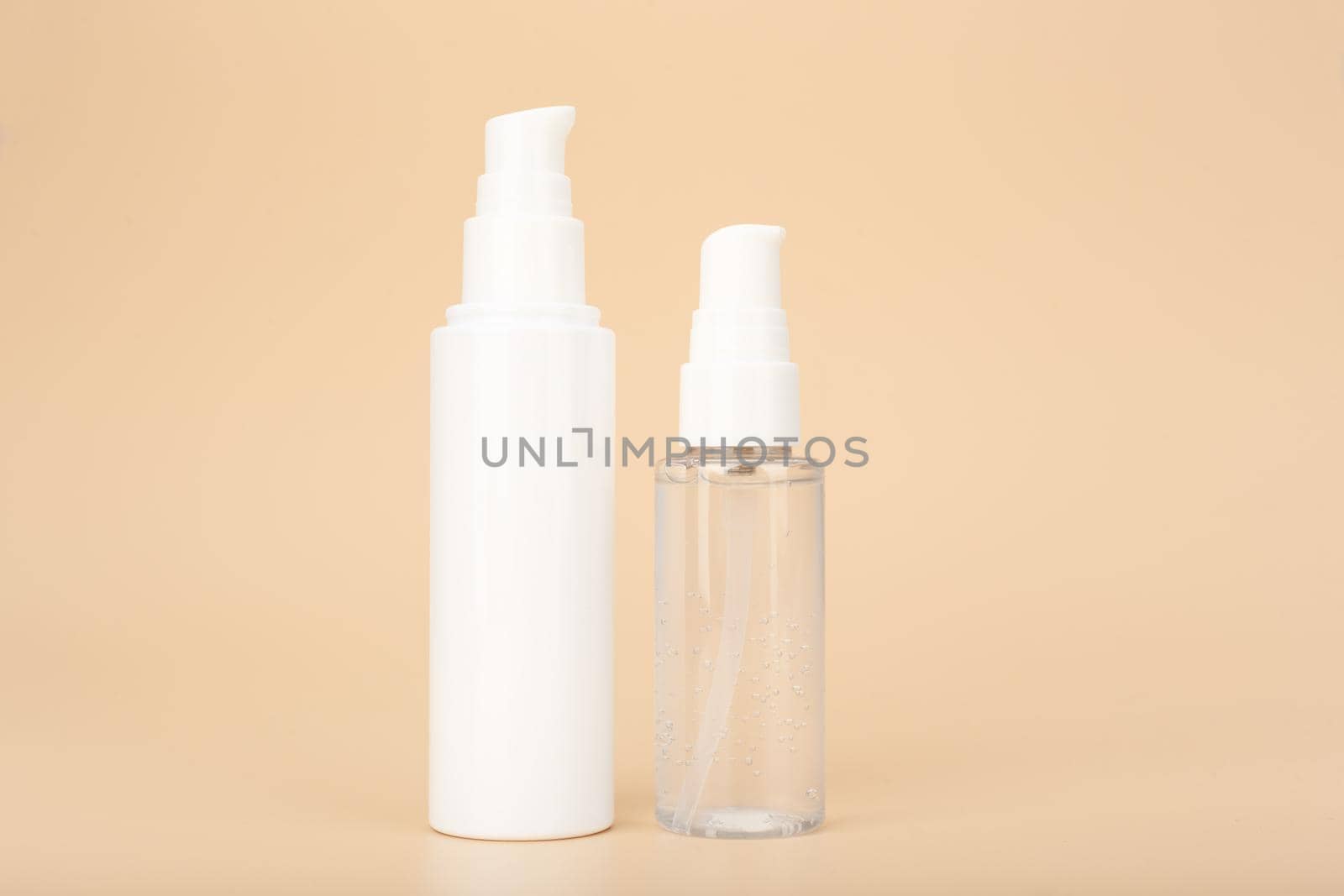 Concept of skin care and beauty products for daily skin care. Transparent bottle with liquid face gel or foam and skin cream or lotion against bright beige background with copy space