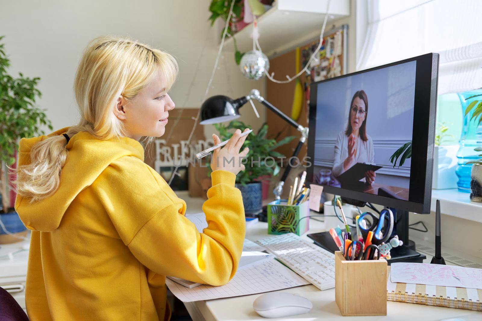 Teenage student female talking, writing, studying, looking at teacher on computer monitor screen. Virtual meeting, distance learning, e-education, individual online lesson, tele video technologies