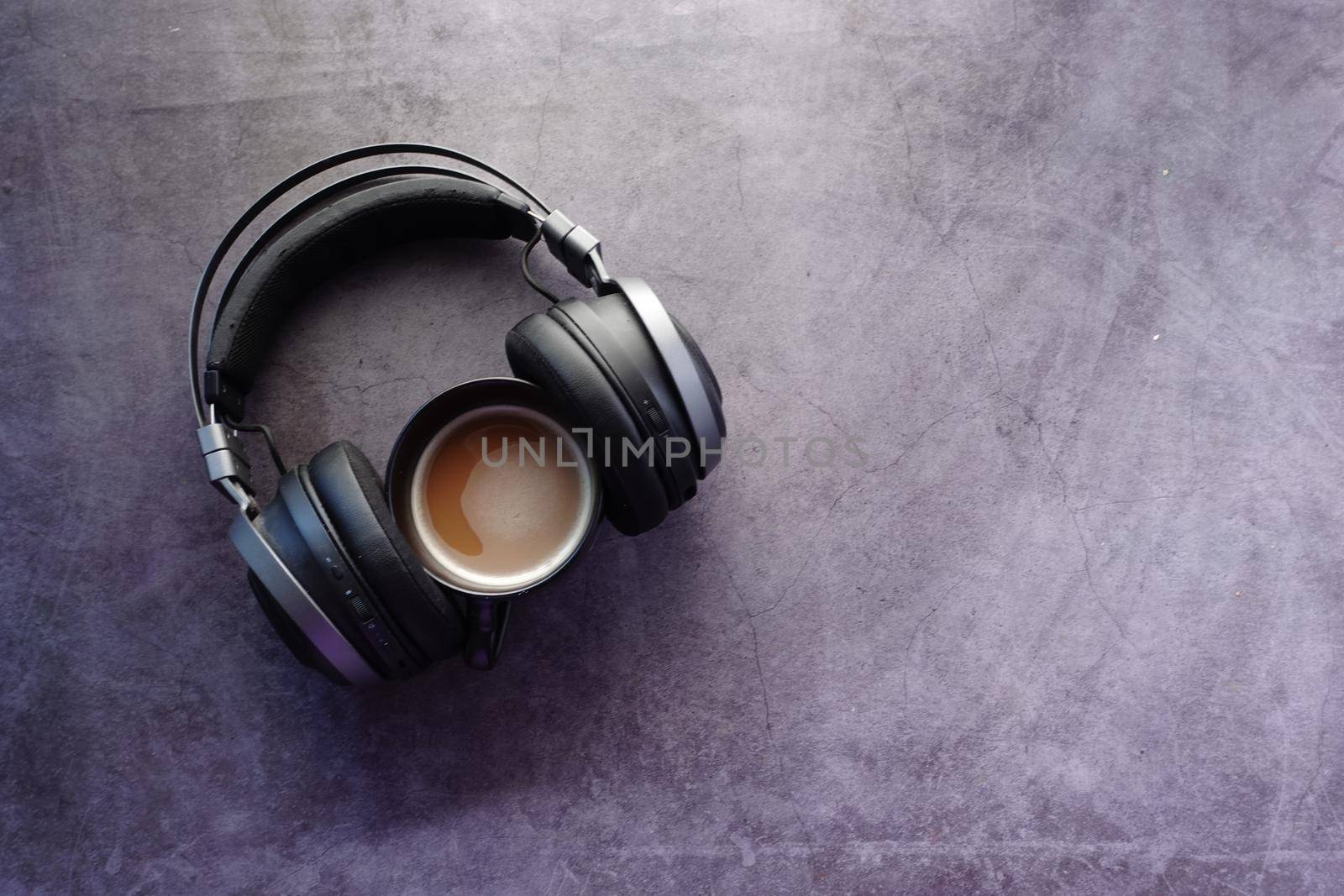 coffee and wireless headphones on black background .