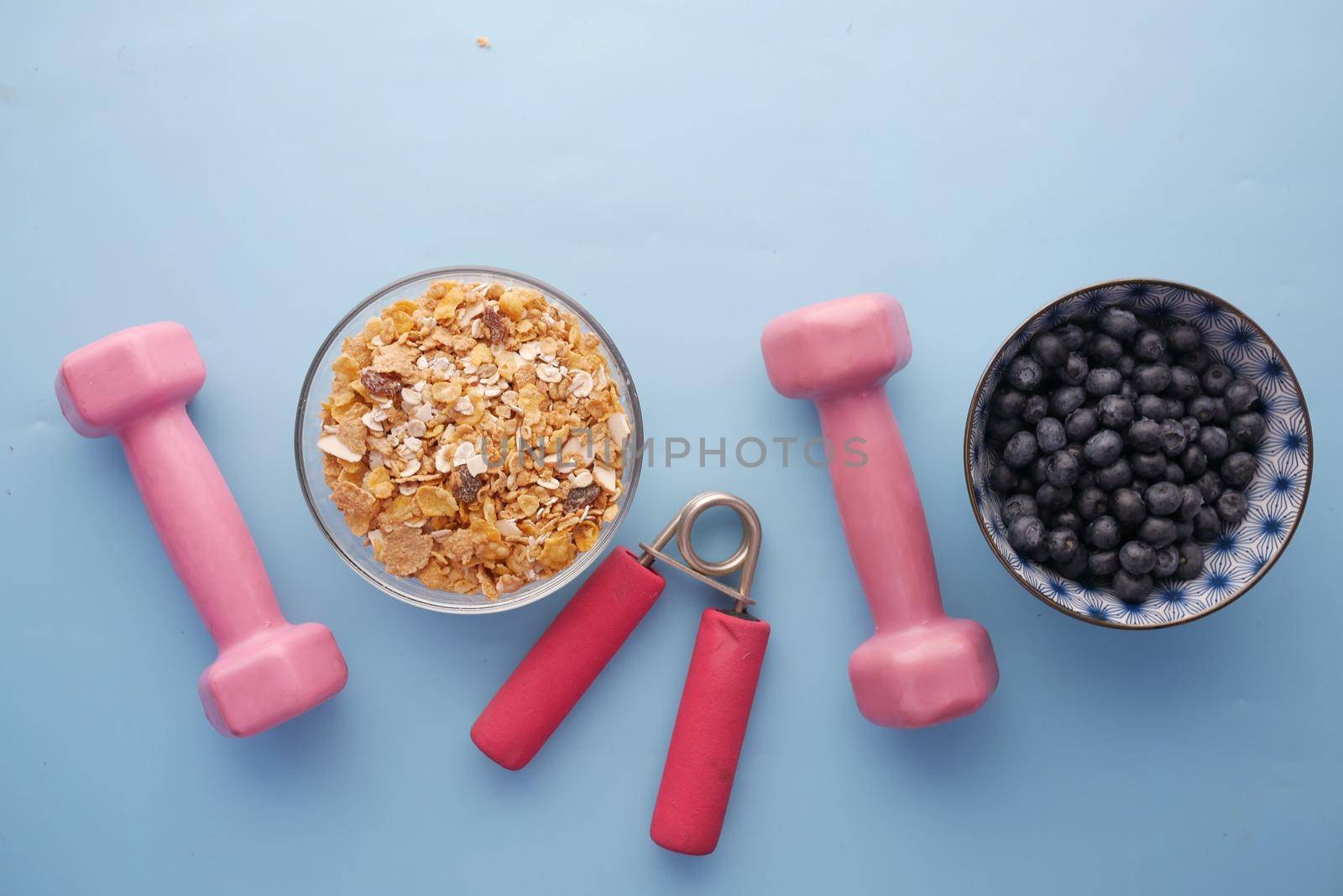 cereal, blue berry and dumbbell on blue background .