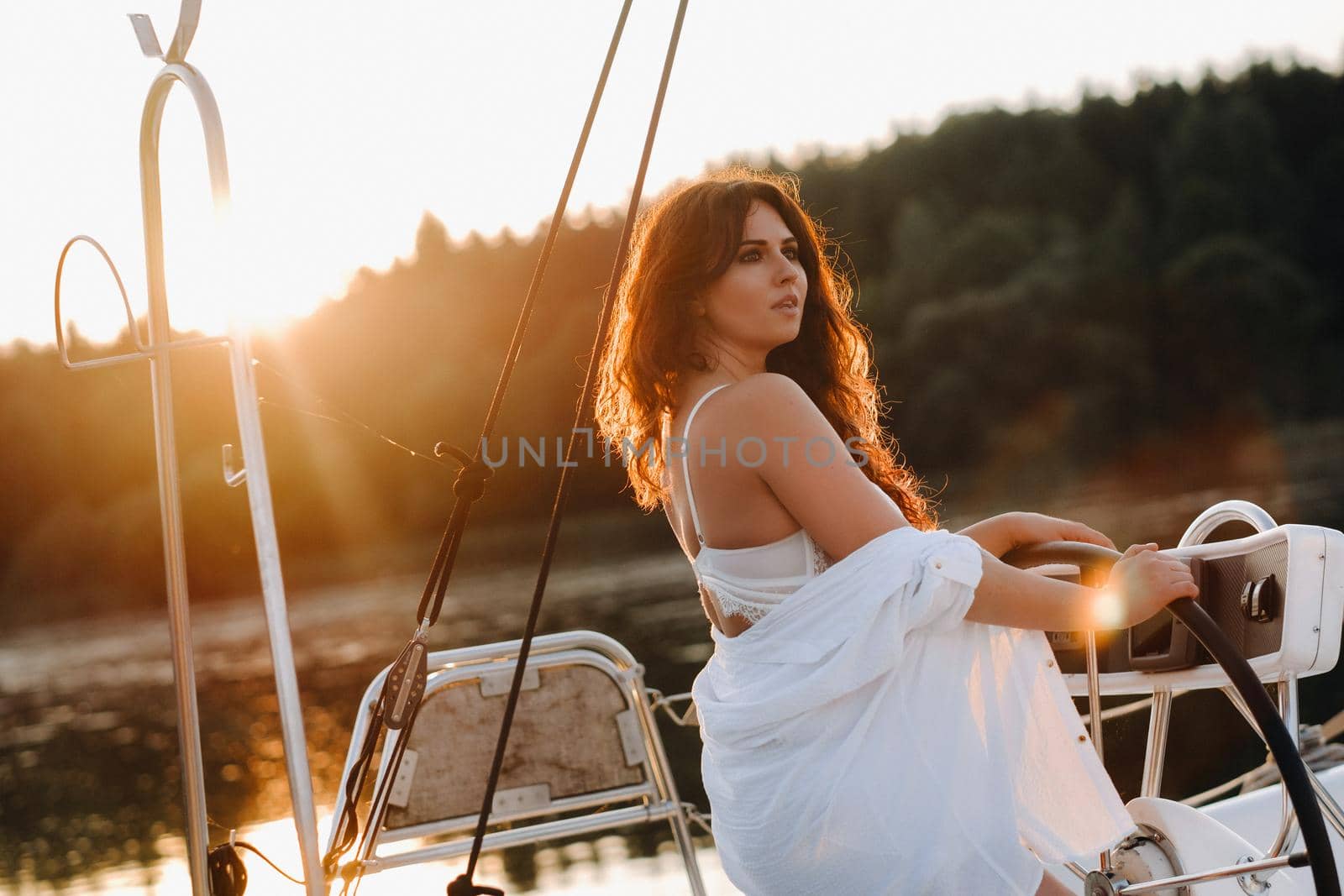 sexy woman in a white shirt enjoys the sunset on her private white yacht.