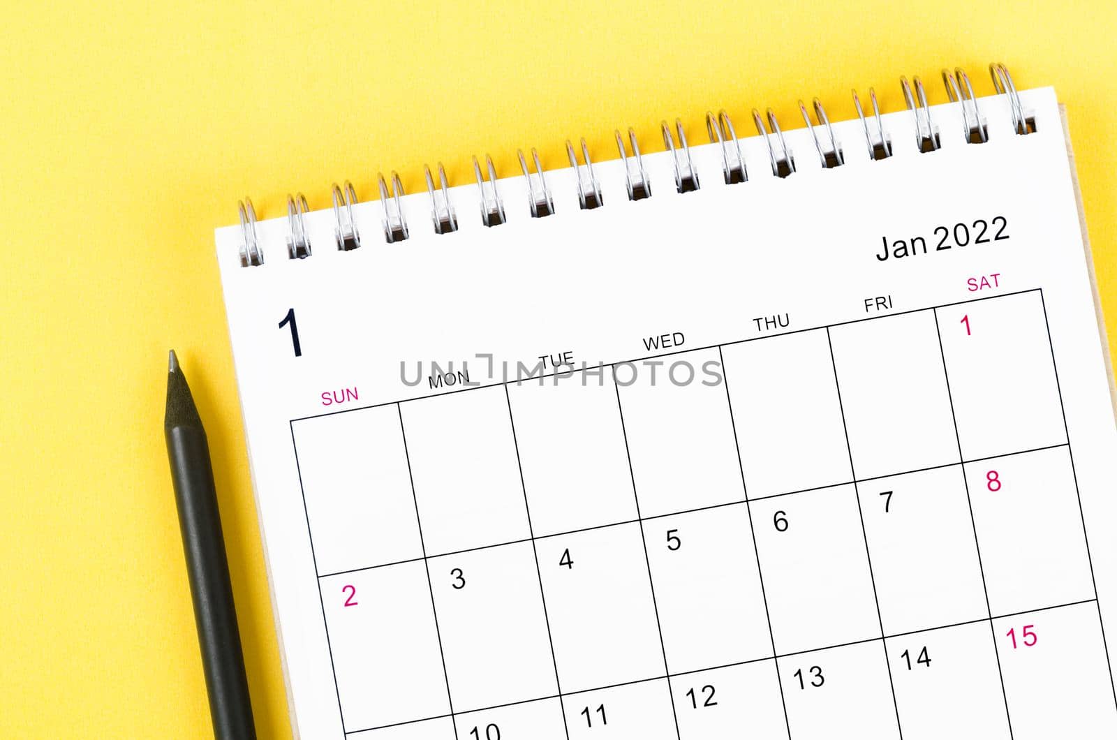 Close-up January 2022 desk calendar on yellow background.