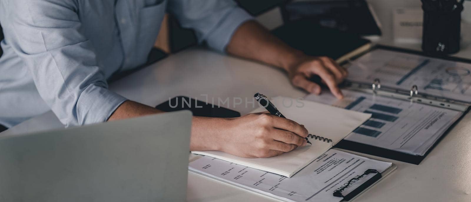 Close up hand of businessman with pen writing on notebook. male working for business financial analysis.