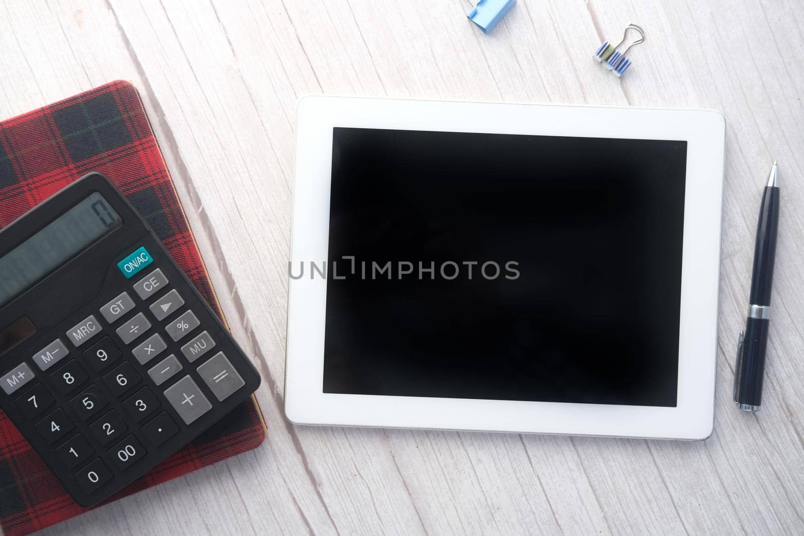 Flat composition of digital tablet and office stationary on black background .