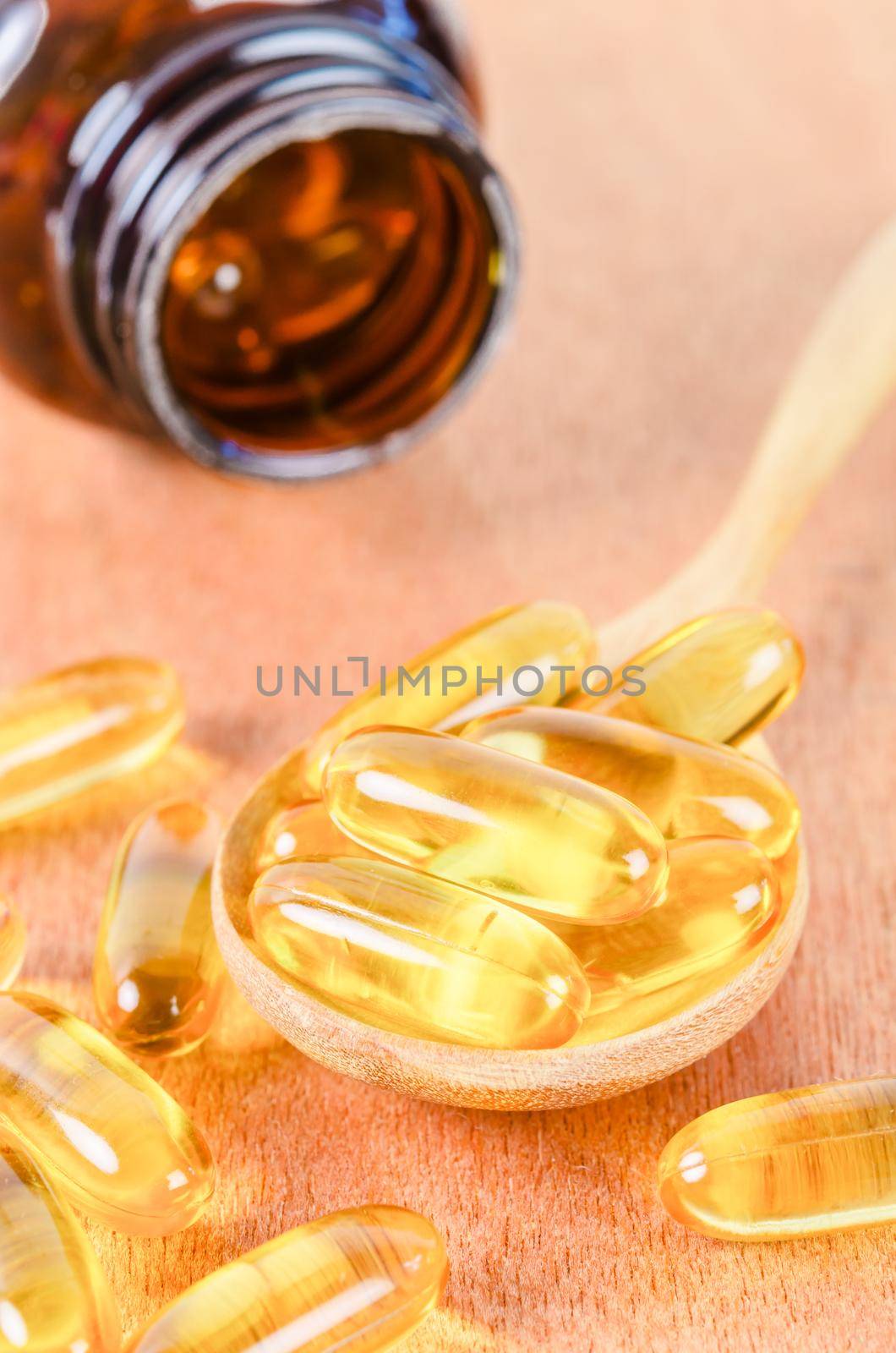 fish oil capsules in wooden spoon on wooden background