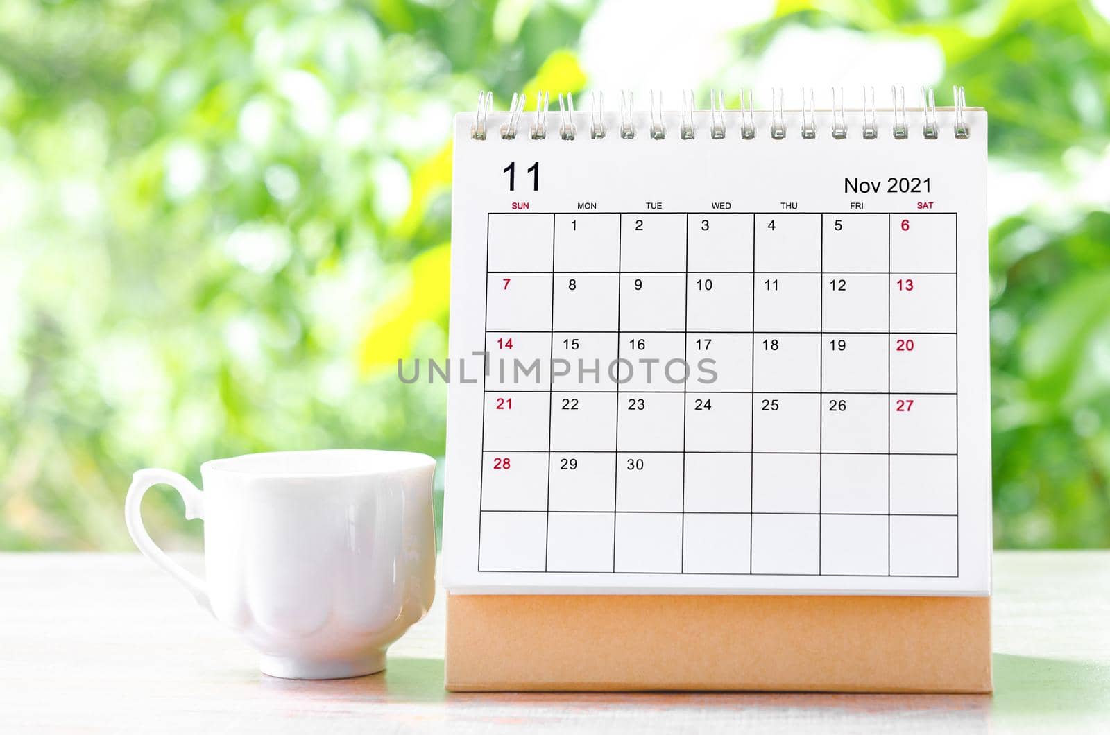 November 2021 Calendar desk for organizer to plan and reminder on wooden table on nature background.