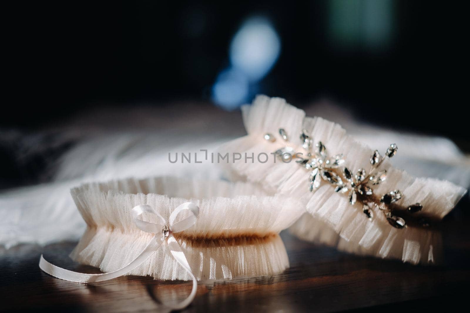 Two white garters of the bride are lying on the table.