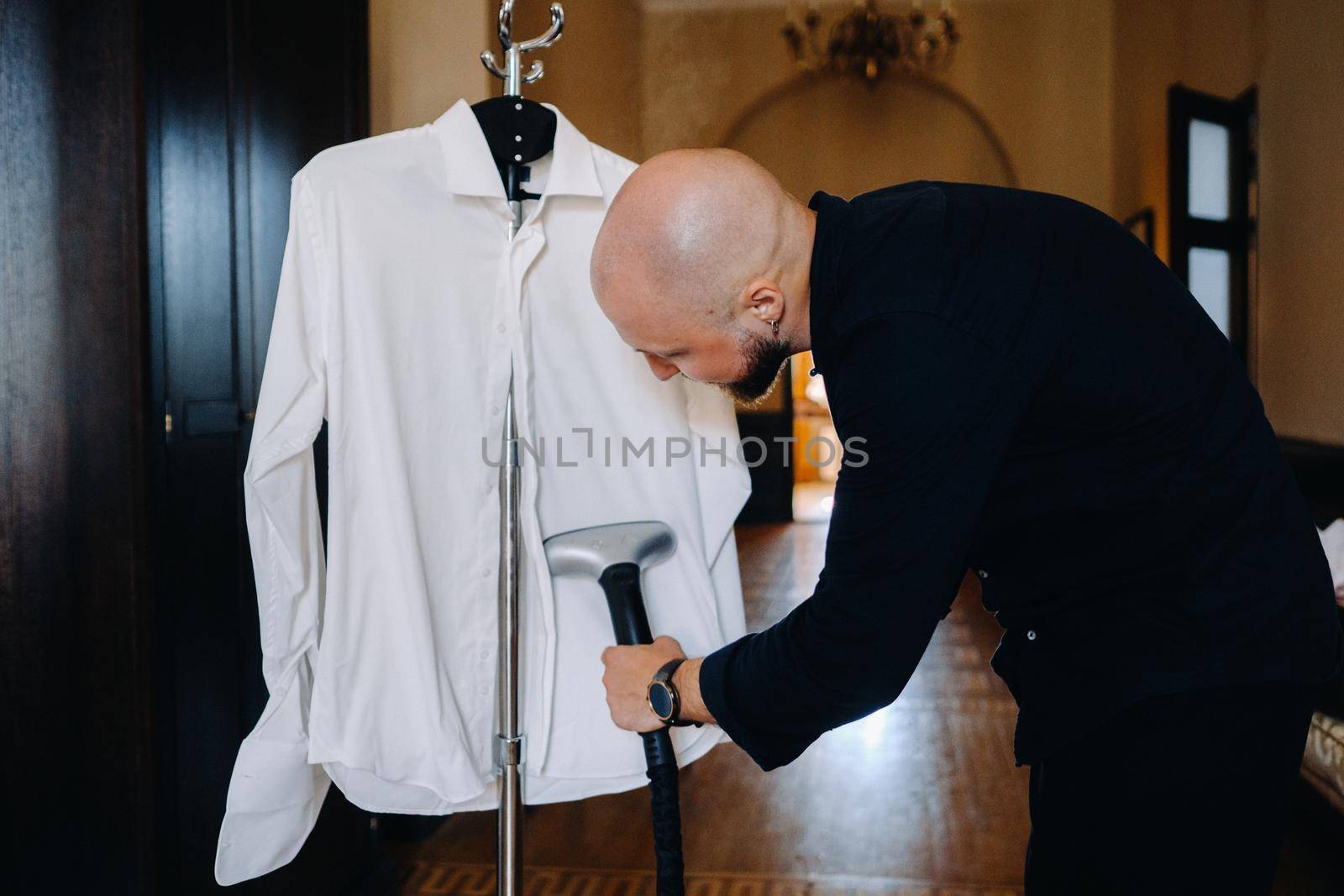 A lonely man is going to work and ironing his shirt with a steam iron.
