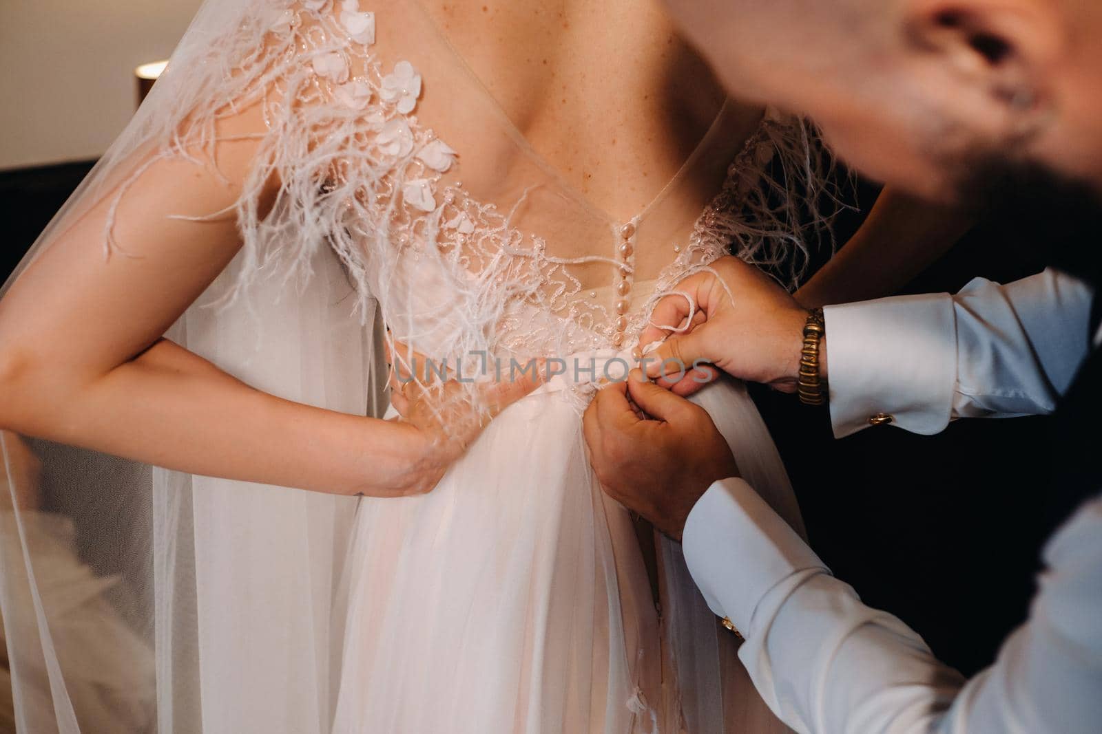 Morning of the bride. The groom helps to dress the bride in a wedding dress.