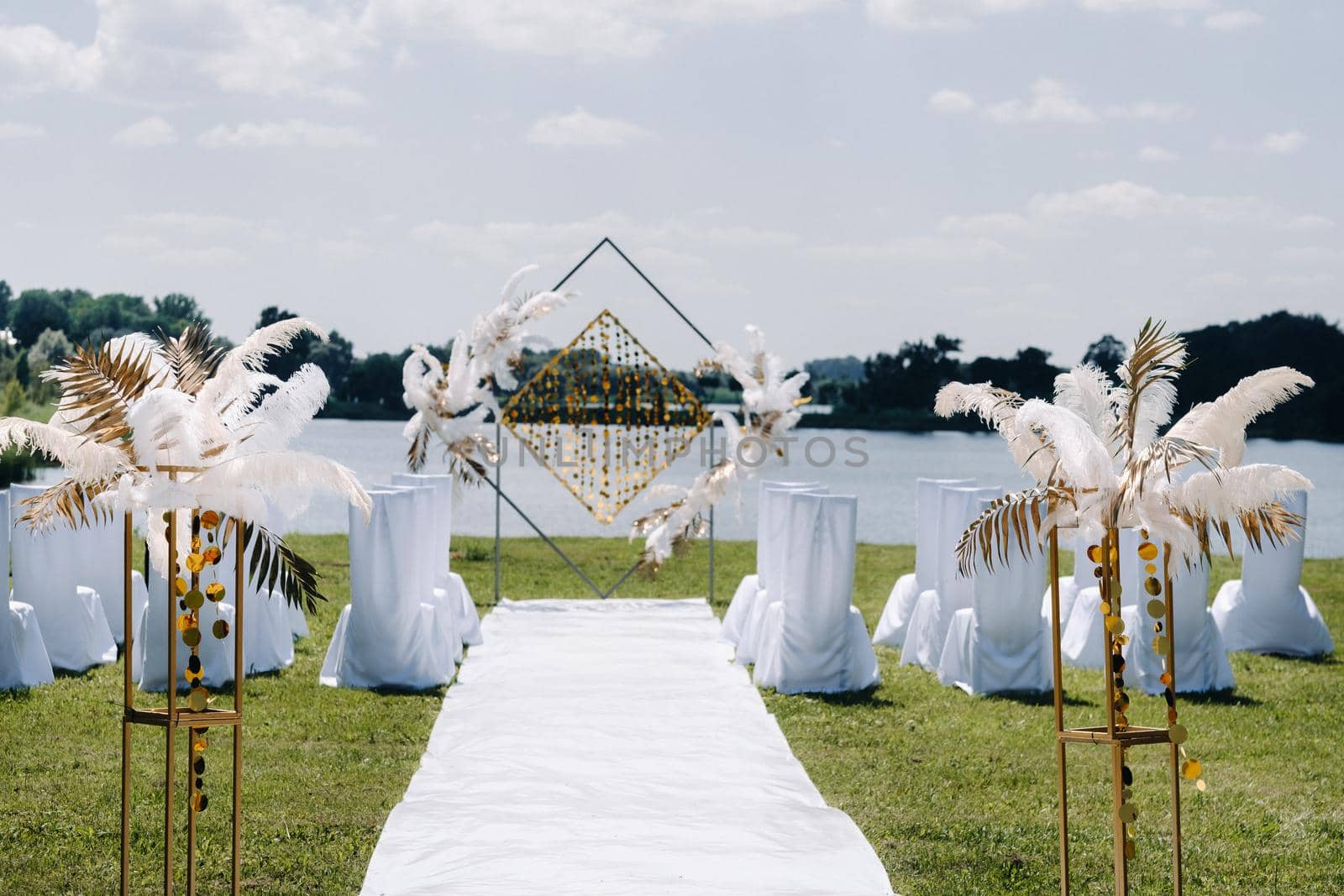 Decorated wedding arch in nature.Wedding ceremony with an arch decorated with retro-style feathers on a lake background.