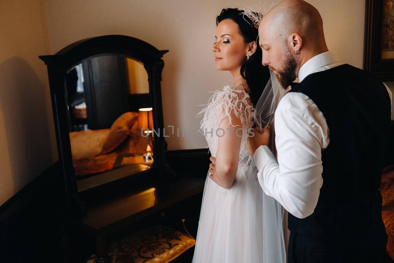 Morning of the bride. The groom stands with the bride near the mirror.