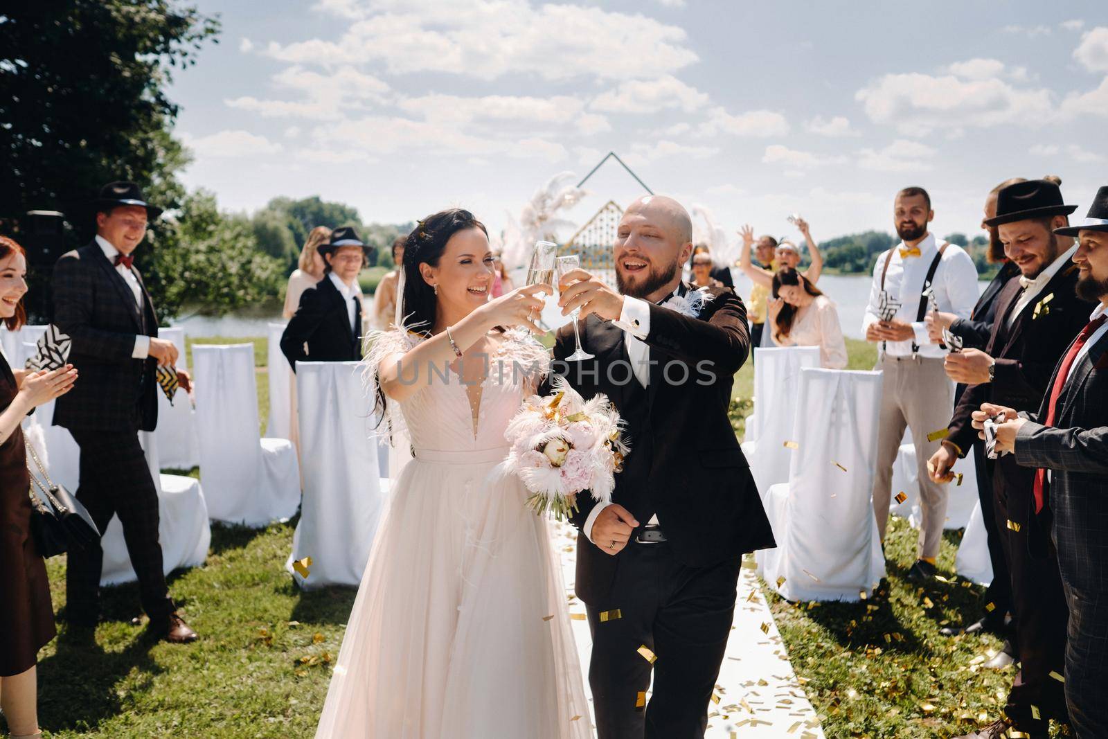 08.07.2021. Nesvizh.Belarus. A happy wedding couple with glasses of wine passes along the guests after the wedding ceremony by Lobachad