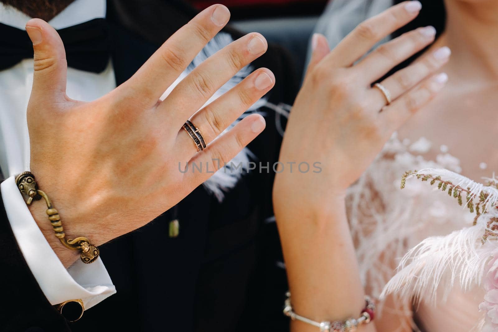 Close-up of the palms of the bride and groom with wedding rings on their hands by Lobachad