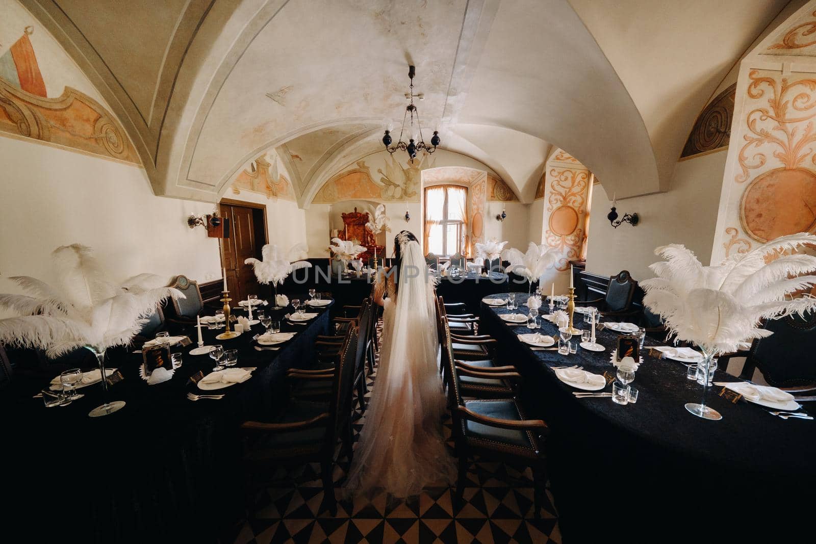 A stylish bride in a wedding dress in the interior of a restaurant decorated with feathers on the tables.