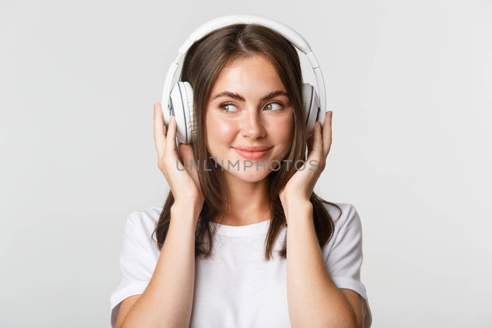 Close-up of smiling attractive brunette girl listening music in headphones, enjoying interesting podcast by Benzoix