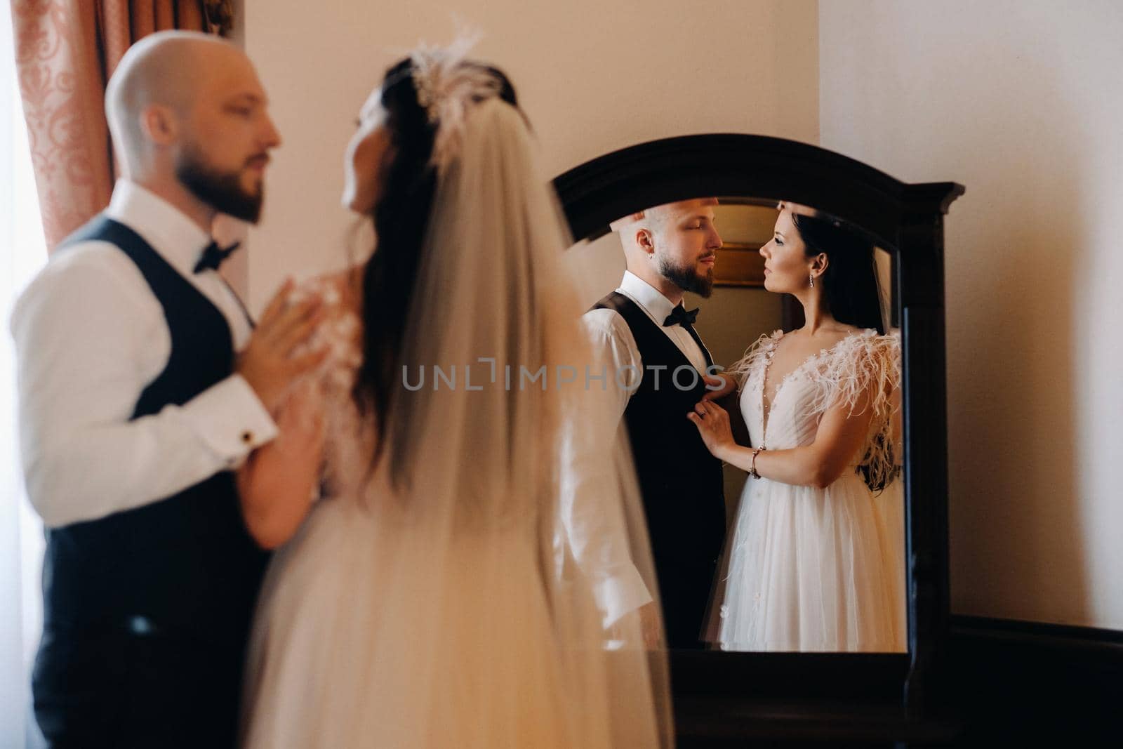 Morning of the bride. The groom stands with the bride near the mirror by Lobachad