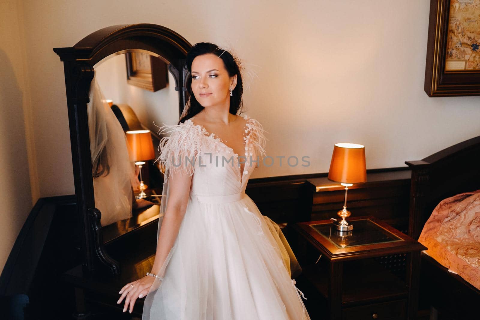 Portrait of the Bride in a wedding dress in the interior of the house near the mirror.