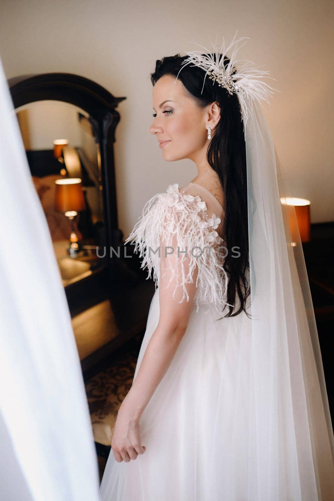 Portrait of the Bride in a wedding dress in the interior of the house near the mirror.