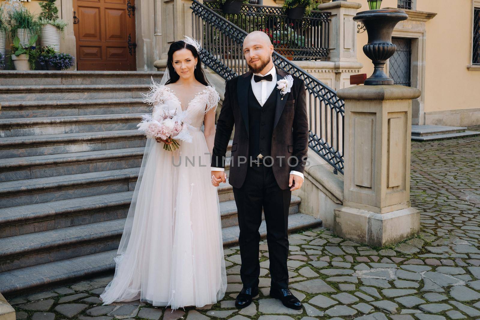 The bride and groom walk up the stairs of the Nesvizh Castle.The wedding couple descend from the stairs of the palace by Lobachad