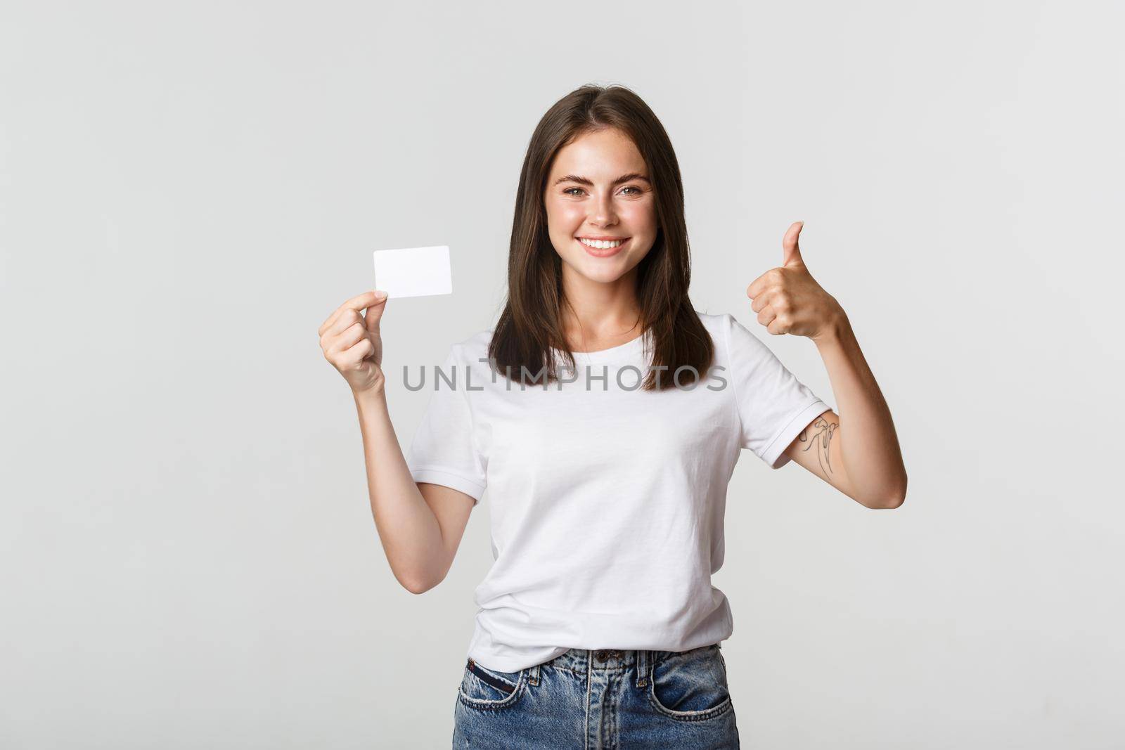 Satisfied attractive girl showing credit card and thumbs-up.